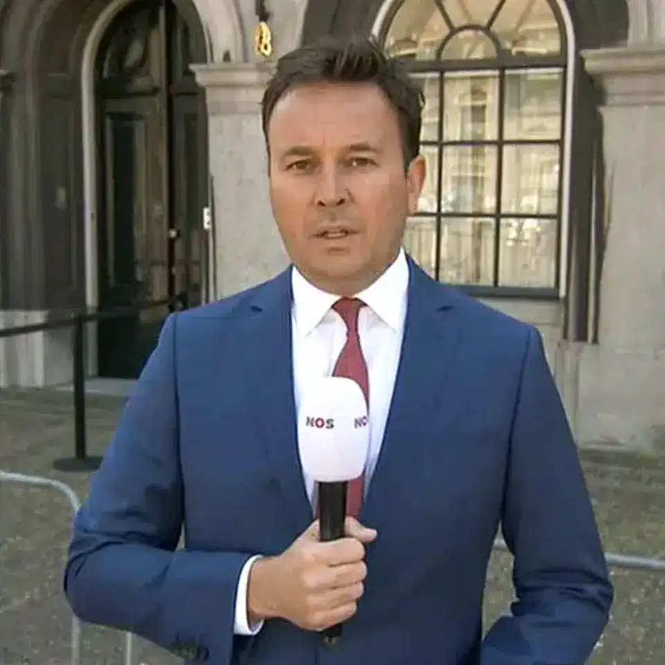 maatpak-klanten-2026-0002 Nieuwslezer Xander van der Wulp in een blauw maatpak met een wit shirt en een rode das van Rietbergh op het Binnenhof in Den Haag